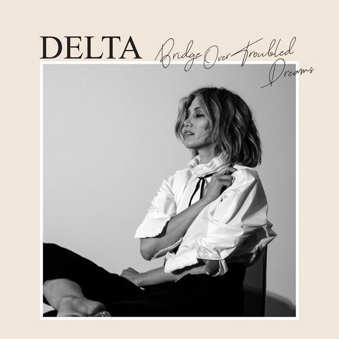 Album cover with Goodrem sitting and text 'DELTA Bridge Over Troubled Dreams' on a beige background