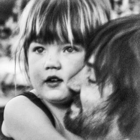 Black and white photo of a child with a person's shoulder in the foreground