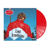 MGK wearing a red jacket with 'Lost Americana' on it against a blue sky with red Vinyl 