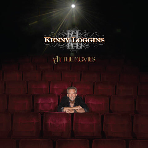 Cover art for Kenny Loggins album 'At the Movies' featuring Kenny Loggins sitting in a movie theater with a spotlight on him.