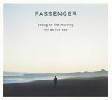 A person standing on a beach looking out towards the ocean, with the text 'PASSENGER young as the morning old as the sea' overlaid on top.