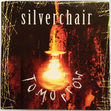 This image features the album cover of "Silverchair - Tomorrow" on a flaming colored vinyl edition. The artwork displays a vivid image of a bright orange, flaming light bulb that consumes the entire frame, creating a striking contrast against the dark, gridded background.