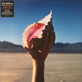 The image shows the cover of the album 'Wonderful Wonderful' by The Killers. It features a hand holding a seashell against a backdrop of a dry, arid landscape under a clear sky.